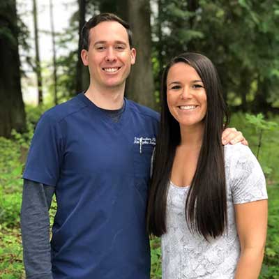 Co-Owners of Nearing Total Health Emily and Eric, Co-Owners of Nearing Total Health, pictured standing in front of a green forest
