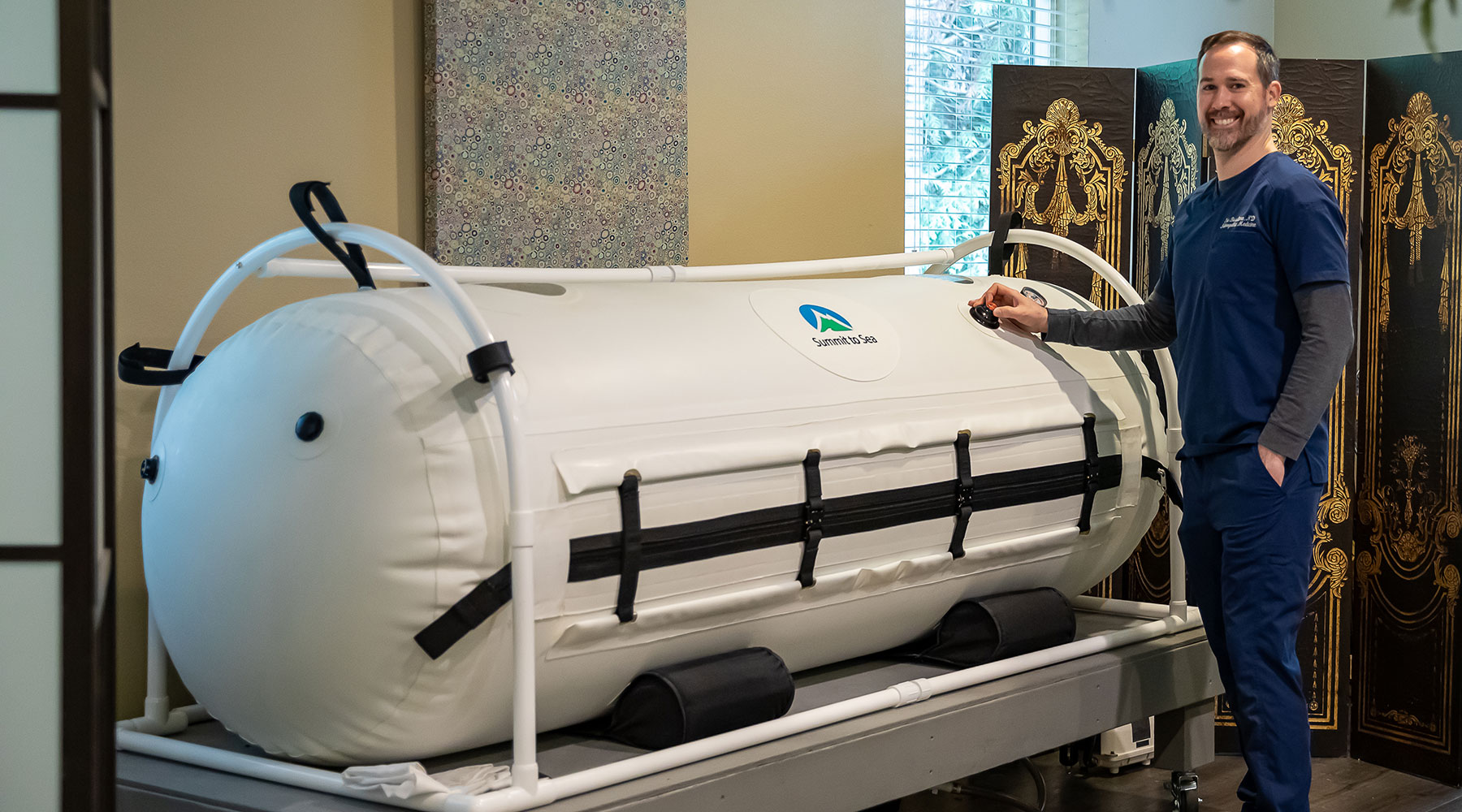 Dr. Eric Basiliere standing in front of the Hyperbaric Oxygen Chamber