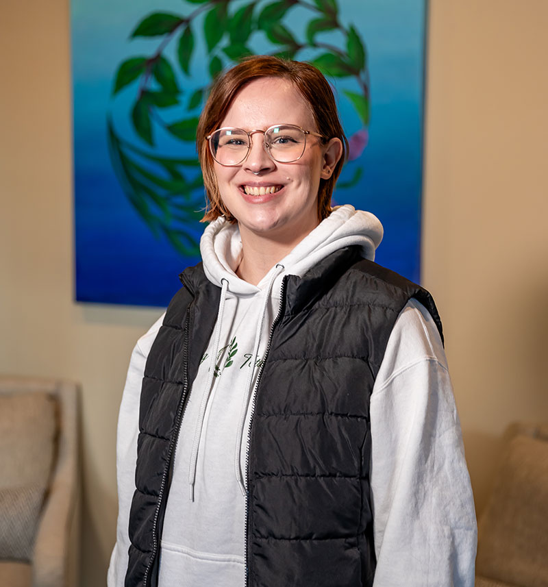 Maggie Andrus standing in front of the Nearing Total Health logo